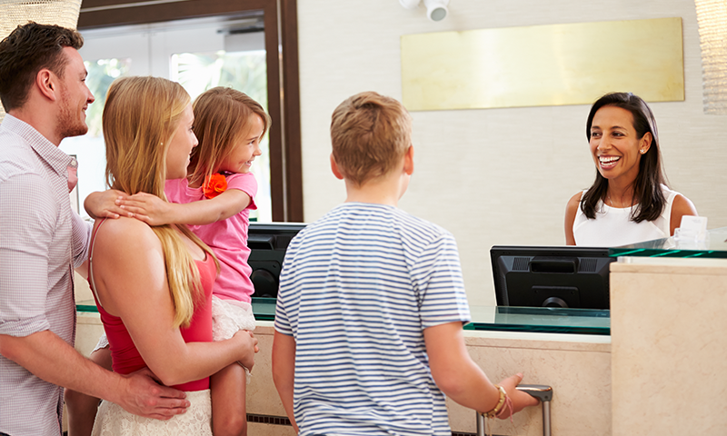 Family Checking In At Hotel Reception