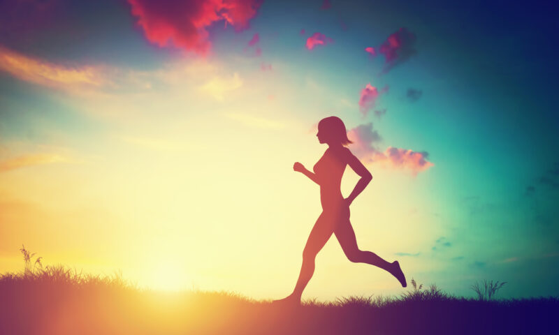 Silhouette of a fit woman running at sunset