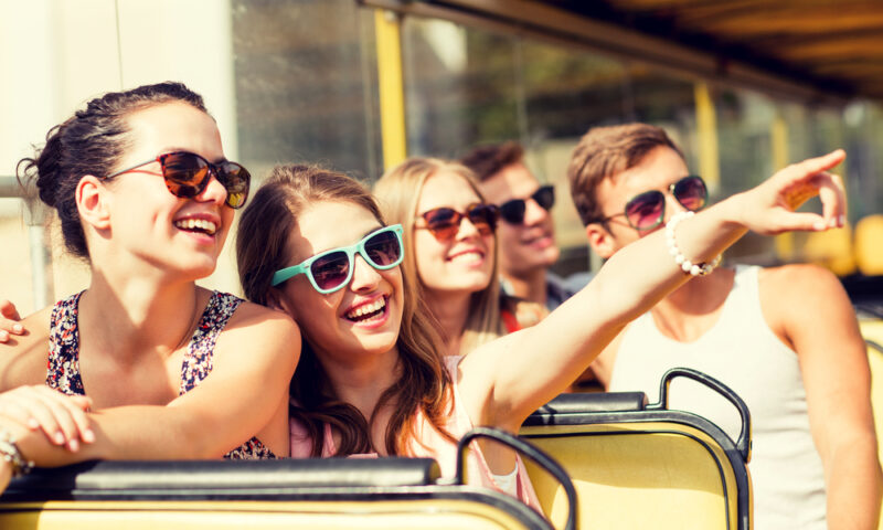 Group of smiling friends traveling by tour bus